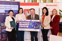 grupa ludzi stoi trzymając symboliczny czek